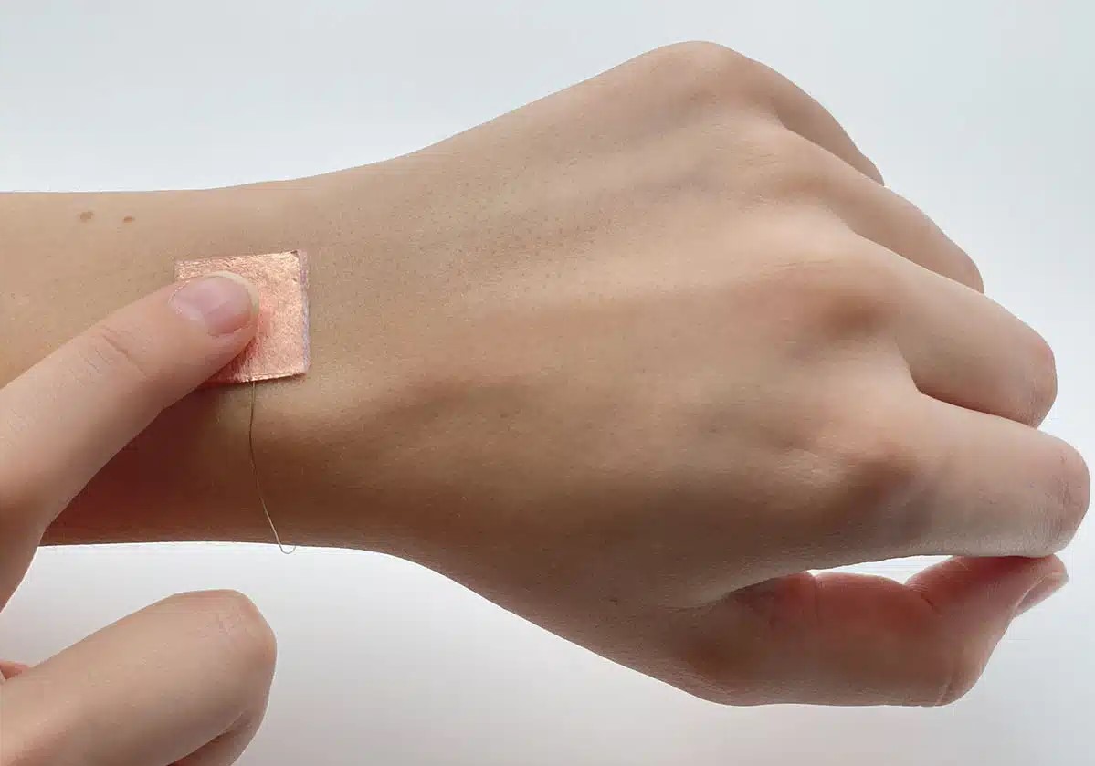 Hand wearing small square of tech material