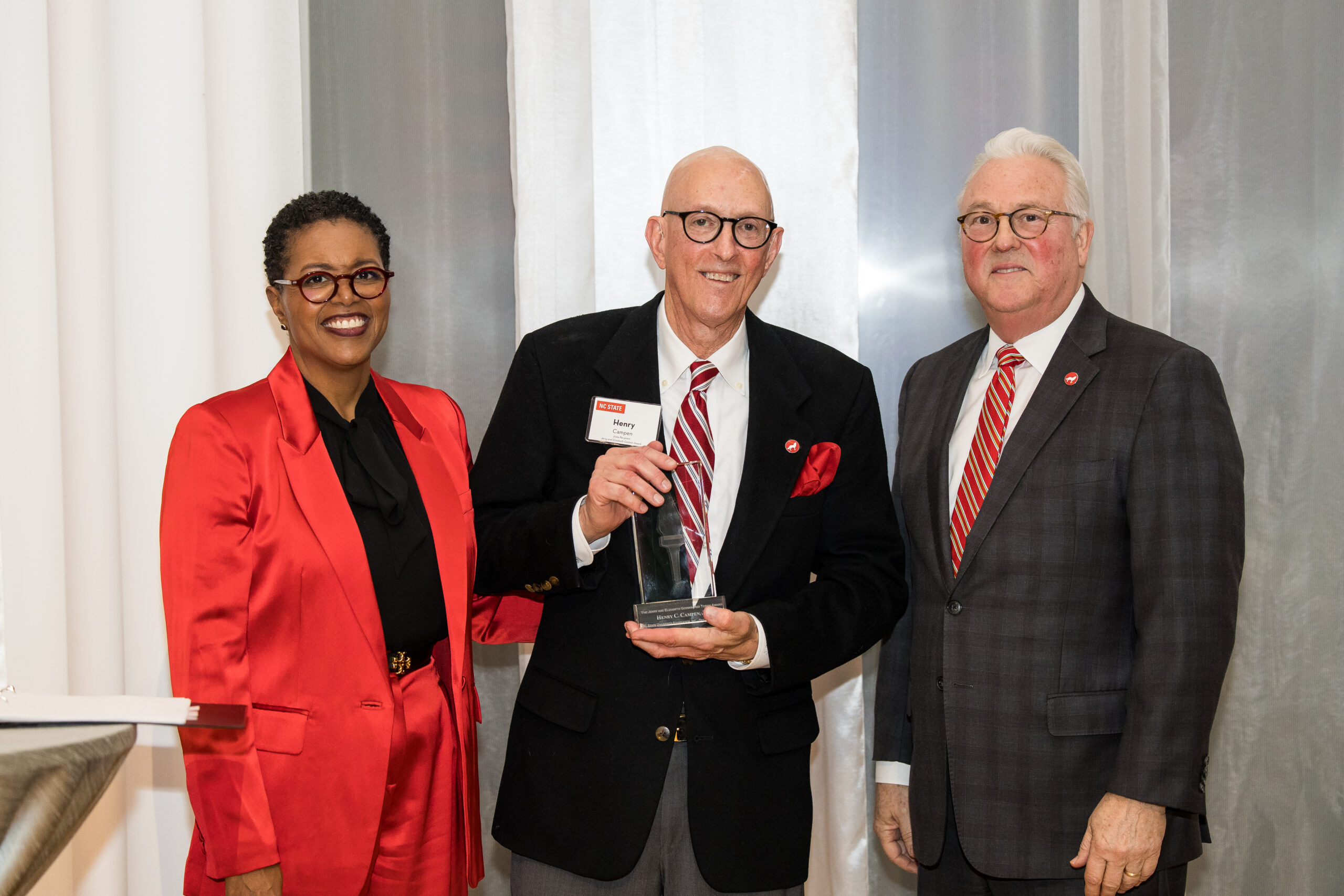 Henry Campen Jr. receives Godwin Red Torch Award next to Bentina Terry and Chancellor Randy Woodson. 