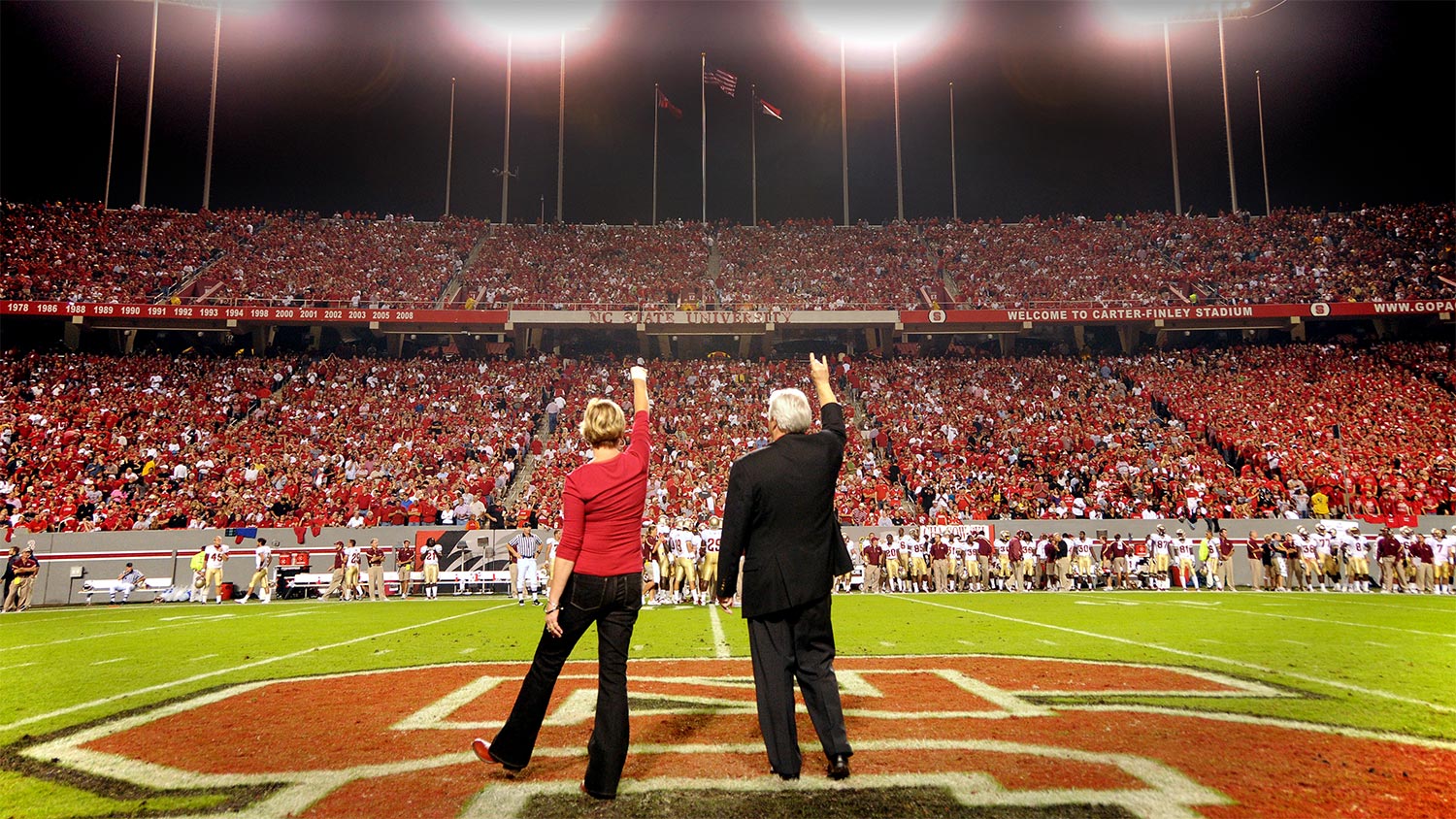 Chancellor Woodson and his wife, Susan, facing the crowd while being introduced during a football game