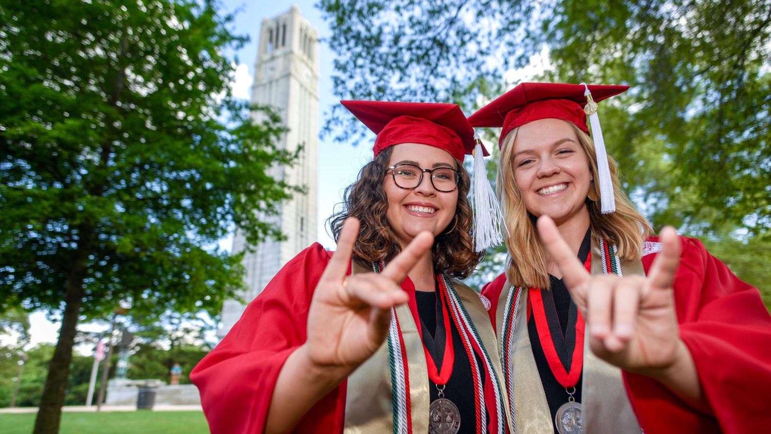 Cashie Naylor and Emily Fletcher in their caps and gowns in front of the Belltower