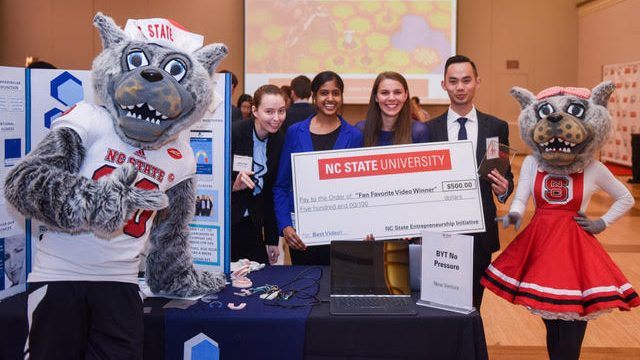 student entrepreneurs posing with the Wufs and a large check.