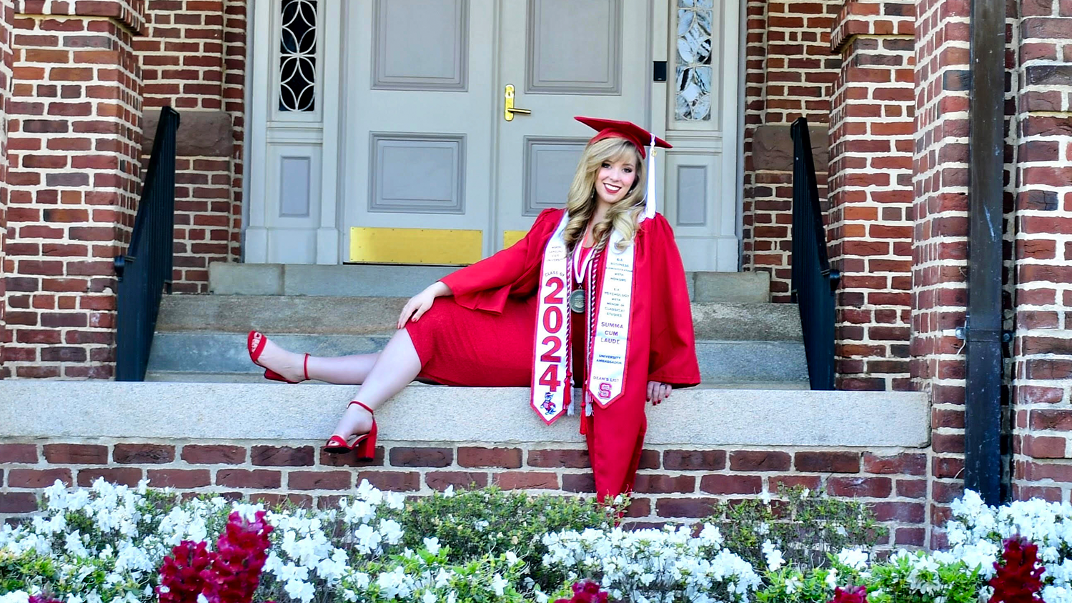 Samantha Steffanus posing in her cap and gown outside of an NC State building