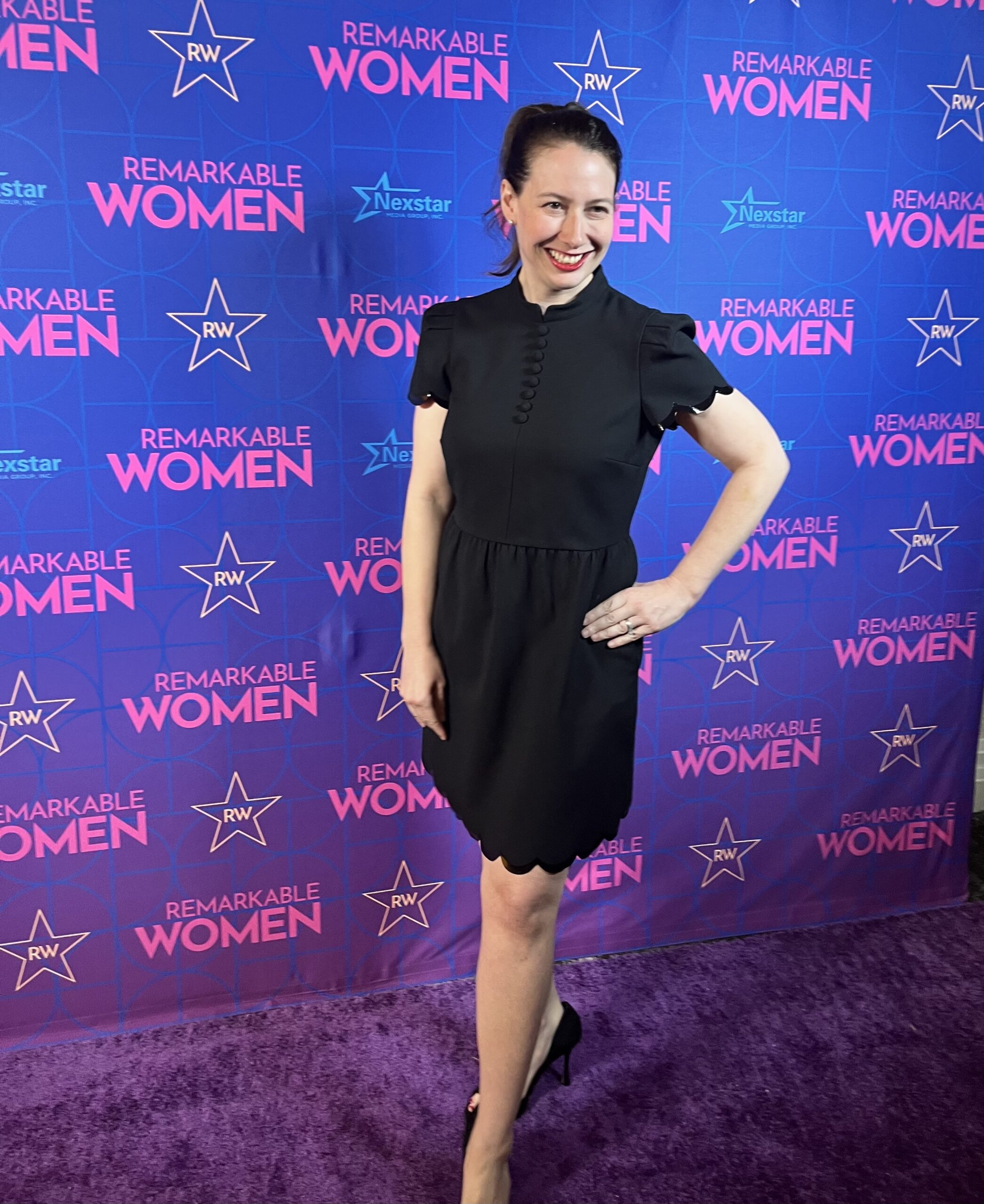 Chasta Hamilton in front of a Remarkable Women step and repeat banner